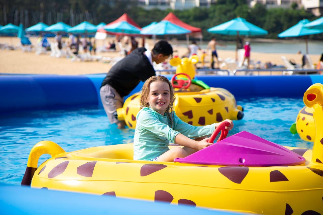 A happy child riding a colorful carousel at a sunny water park, having fun.